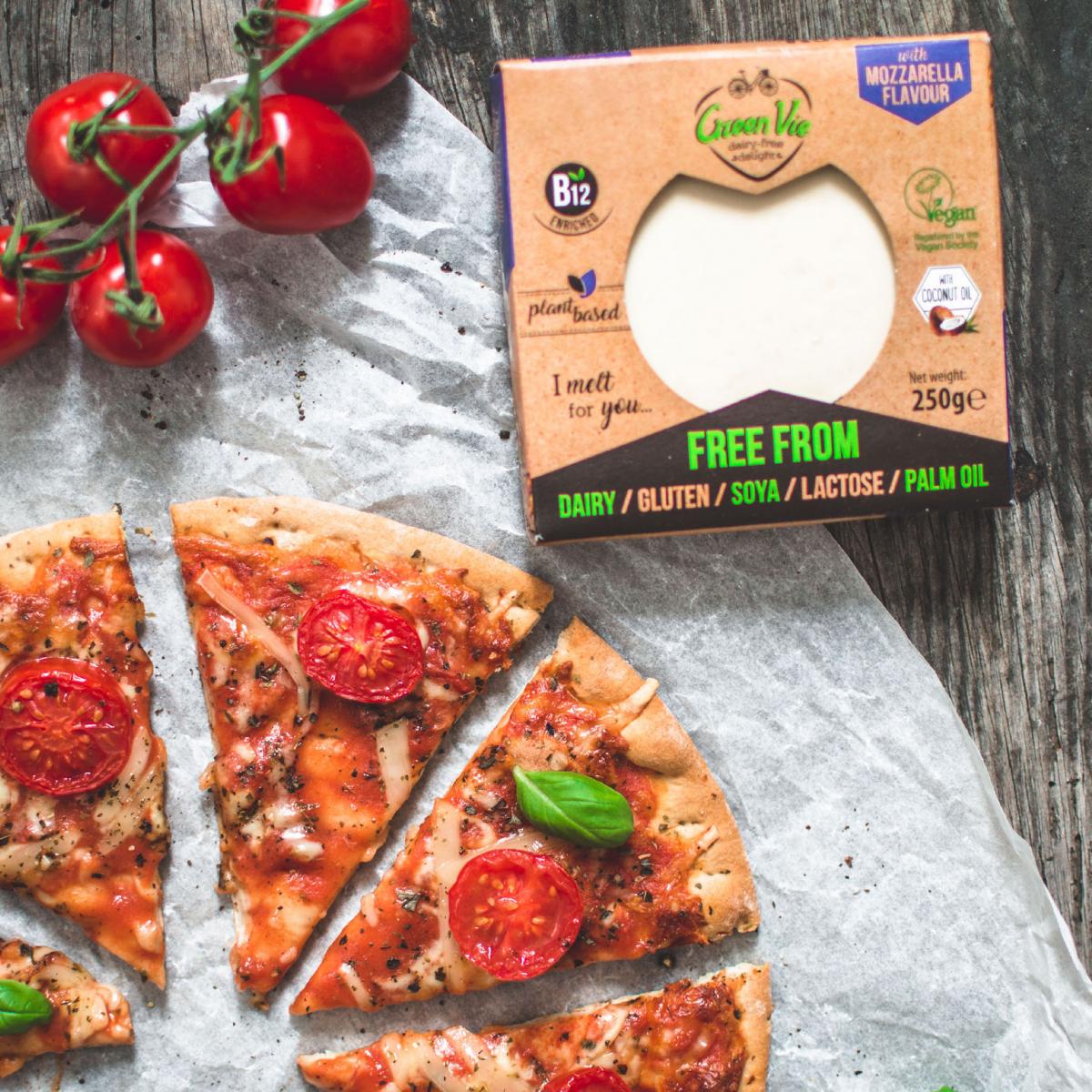 Cheese and tomato pizza cut up next to Green Vie cheese in packaging