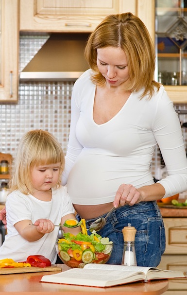pregnant woman and her child making salad