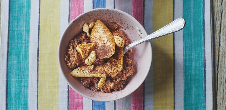 A bowl of baked oats against a colourful striped background