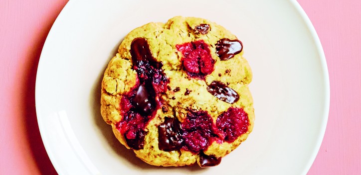 photograph of raspberry and chocolate microwave cookie on a plate against a pink background