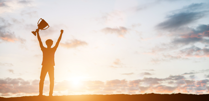 Person holding up a trophy during a sunset
