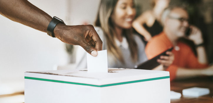 Person dropping vote into a ballot box