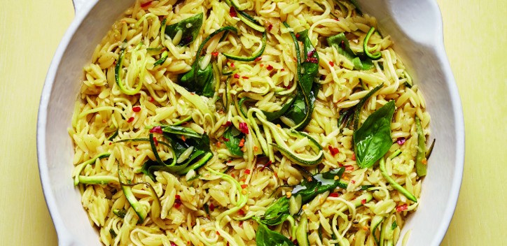 photograph of lemony courgette orzo in a pan against a yellow background