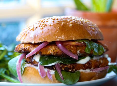 Chickpea & pumpkin burger served with red onions, green leaf and vegan mayonnaise in a bun
