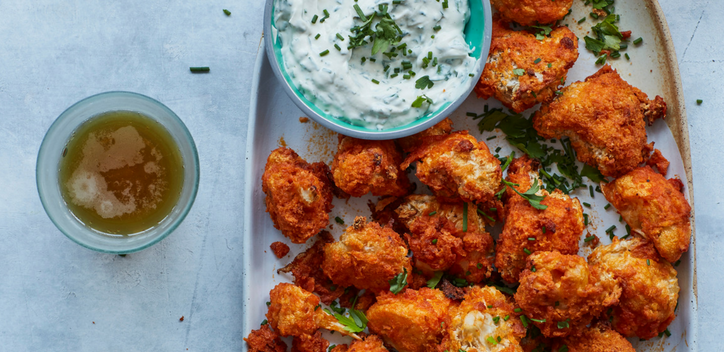 A platter of cauliflower buffalo wings served with a vegan ranch sauce.