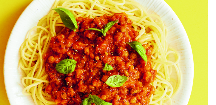 photograph of lentil ragu on a plate against a yellow background