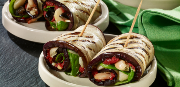 Two plates of butter beans, black olives and tomato puree wrapped in broad aubergine strips