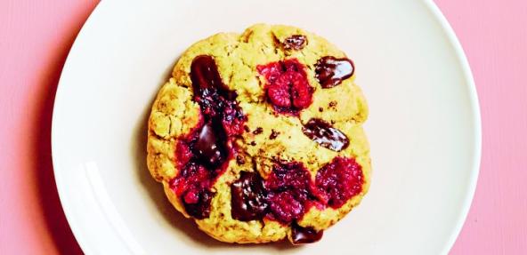 photograph of raspberry and chocolate microwave cookie on a plate against a pink background