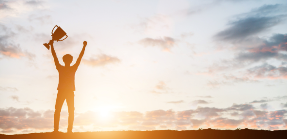 Person holding up a trophy during a sunset