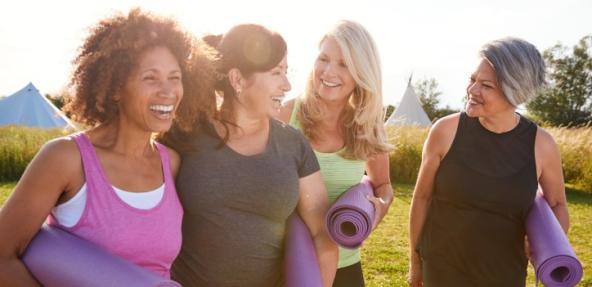 Group of friends outdoors holding yoga mats laughing