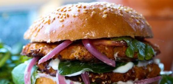 Chickpea & pumpkin burger served with red onions, green leaf and vegan mayonnaise in a bun