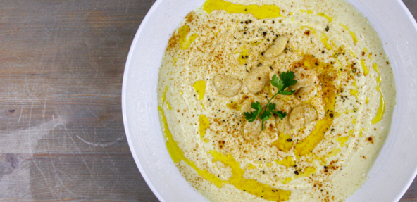 Vegan butter bean hummus in a white bowl with yellow oil over the top