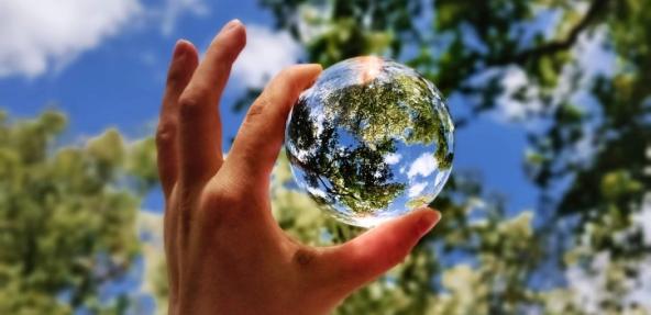 hand holding a globe up to the sky