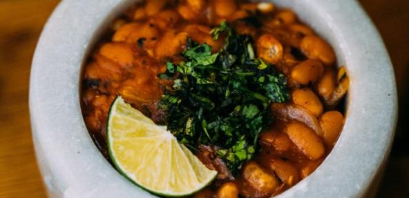 beans in a tomato sauce in a bowl with lime garnish