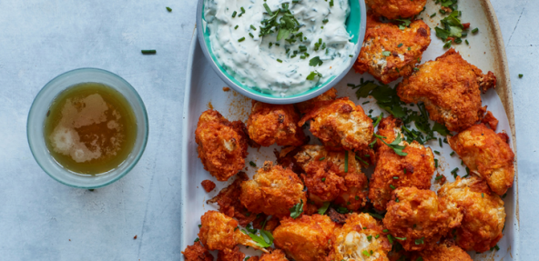 A platter of cauliflower buffalo wings served with a vegan ranch sauce.