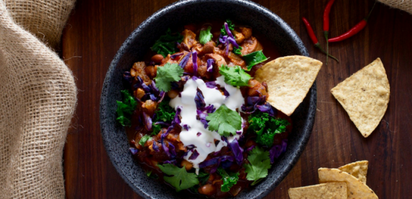 Vegan cauliflower vegetable and bean chili served in a bowl with mini tortilla