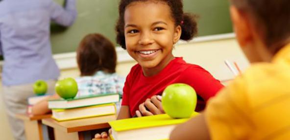 child at school desk turning around to friend 