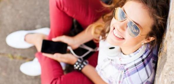 Teenager in red jeans sitting on floor with phone