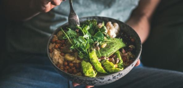 Healthy dinner or lunch. Woman in t-shirt and jeans eating vegan superbowl