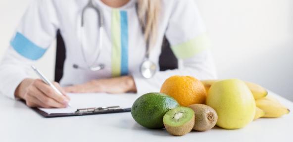 person writing on a clipboard with fruit on the table