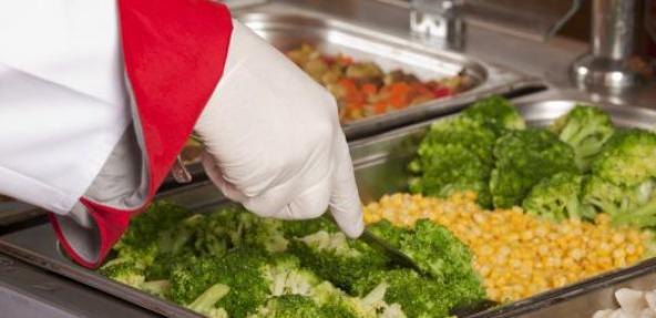 Hand serving up broccoli and sweetcorn in school canteen