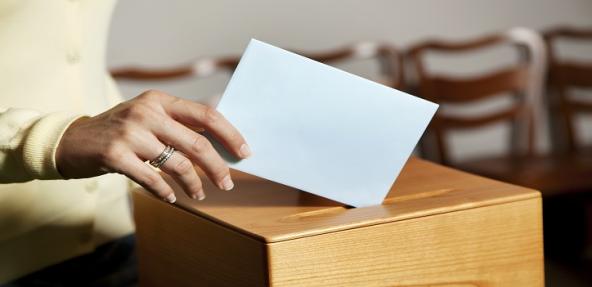 person voting in a ballot box