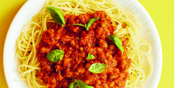 photograph of lentil ragu on a plate against a yellow background