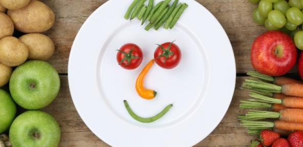 Fruit and veg to the side with a plate of veg in the shape of a face