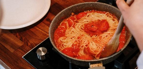 tomato sauce and spaghetti in a pan being stirred