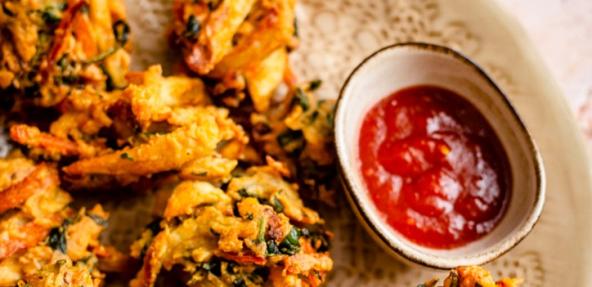 vegan pakora on a plate next to a pot of sauce