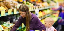 Lady with a baby shopping for fruit and veg in a supermarket
