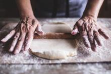 Hands rolling dough with rolling pin