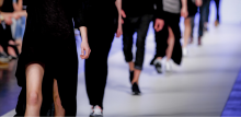 Model on catwalk photographed from the neck down with other models walking behind