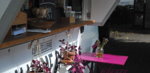 Close up of pink metal table and chairs outside of food van with hanging plant pots 