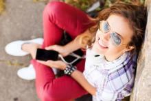 Teenager in red jeans sitting on floor with phone