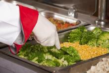 Hand serving up broccoli and sweetcorn in school canteen