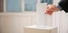 person putting vote into a ballot box