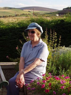 Woman smiling as she sits in a sunny garden