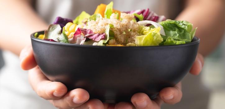 Person holding a bowl of salad