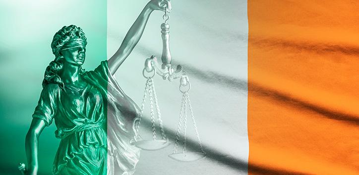 Lady justice statue behind Irish flag