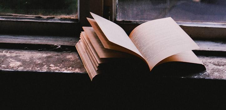 A photograph of an open book on a window ledge.