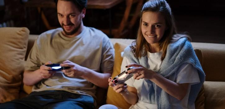 two people sitting down on sofa playing video games