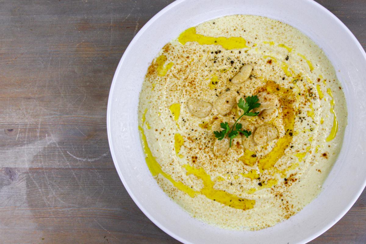 vegan butter bean hummus in a white bowl with yellow oil over the top