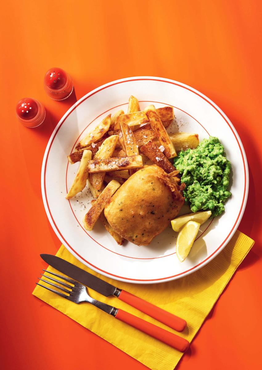 to'fish and chips served on a plate with peas and a wedge of lemon