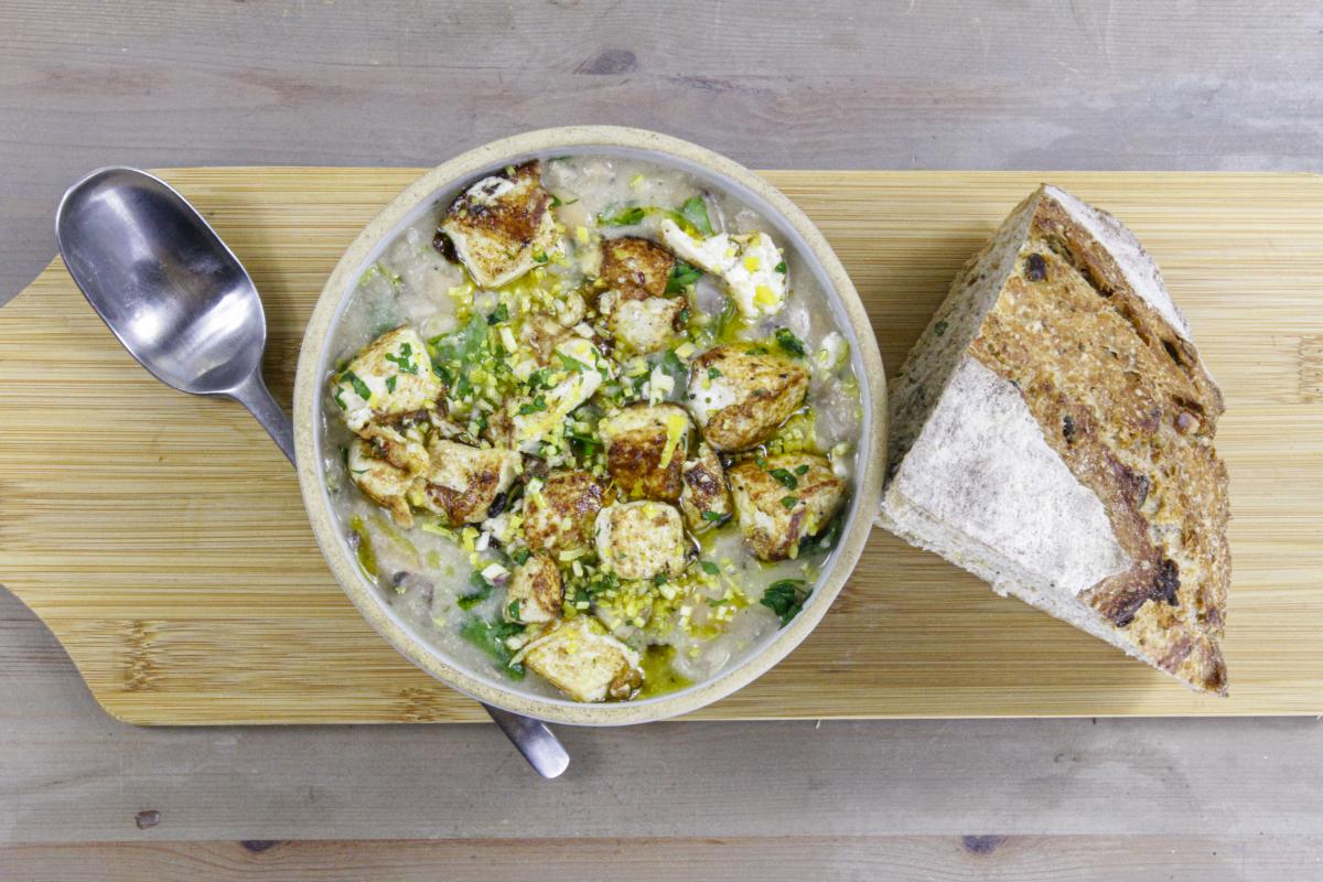 vegan white bean cassoulet and tofu gremolata in a round bowl with a silver spoon to the left 