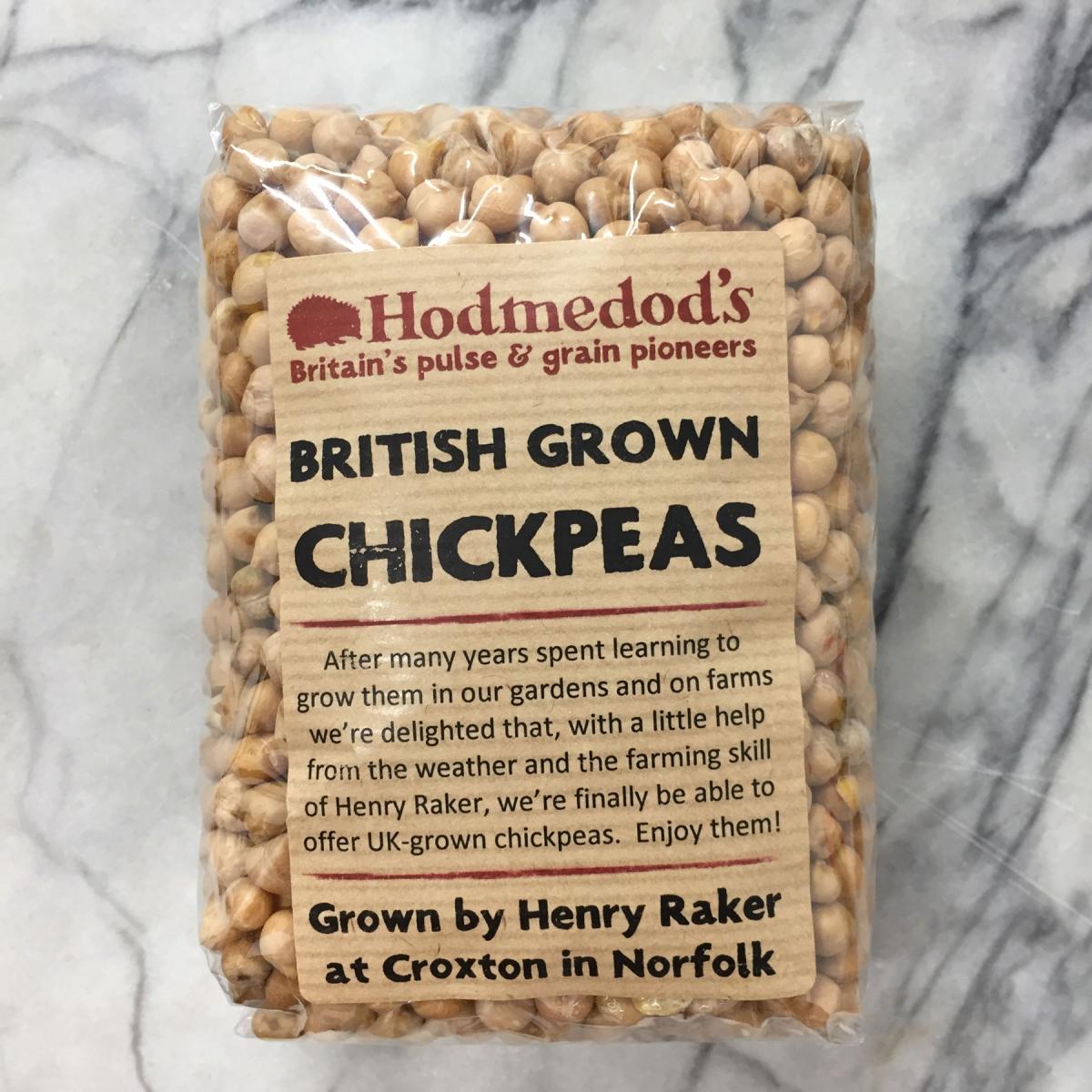 A pack of 2019 British chickpeas.  The Hodmedod’s logo, a hedgehog (which is an East Anglian dialect word meaning ‘curled up’, sometimes applied to hedgehogs), with the strap line ‘British pulse & grain pioneers’ all in brick red, and the description “British Grown Chickpeas.  After many years spent learning to grown them in our gardens and on farms we’re delighted that, with a little help from the weather and the farming skill of Henry Rakers, we’re finally able to offer UK-grown chickpeas.  Enjoy them!  Grown by Henry Raker at Croxton, Norfolk.