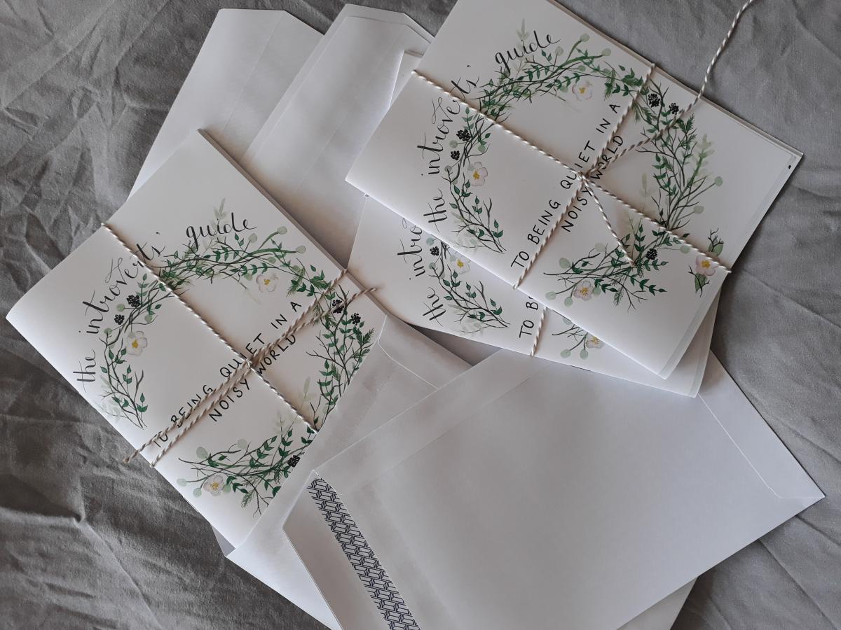 White booklets titled "The Introverts Guide to Being Quiet in a Noisy World" wrapped in string on a grey fabric background