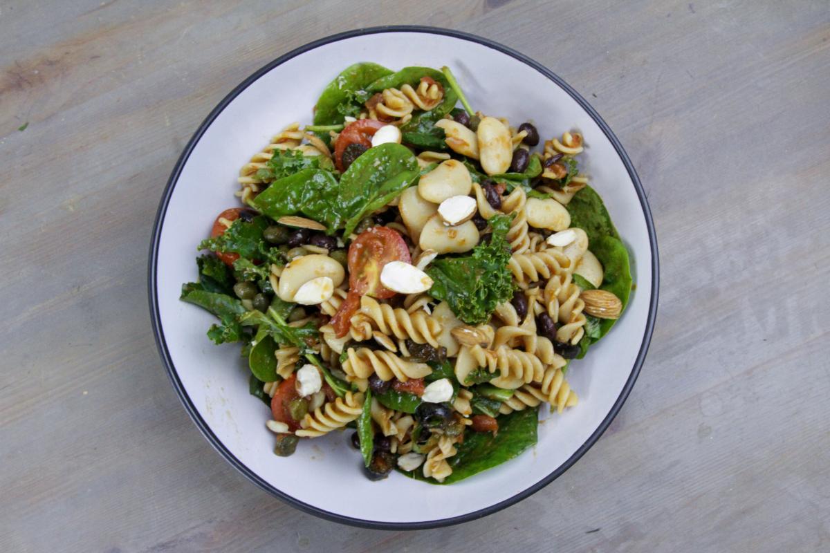 vegan pasta salad in a white bowl with a blue edge against a grey background