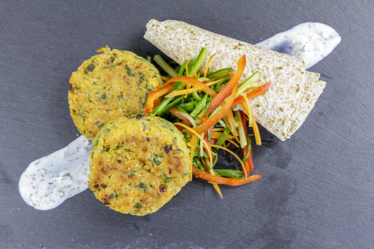 chickpea and coriander patties on a dark slate background with shredded vegetables
