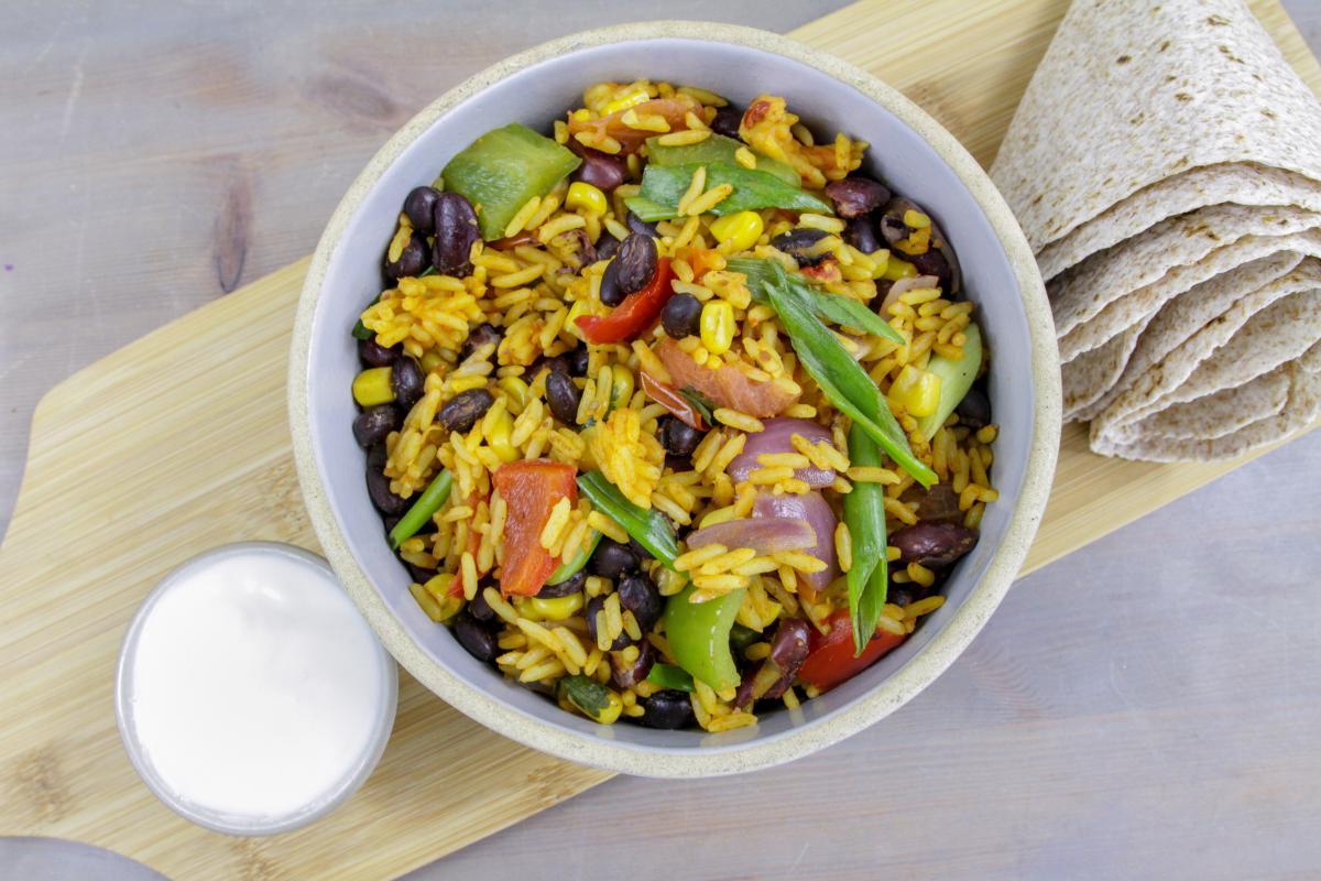 yellow Mexican rice with vegetables, wrap and white sauce